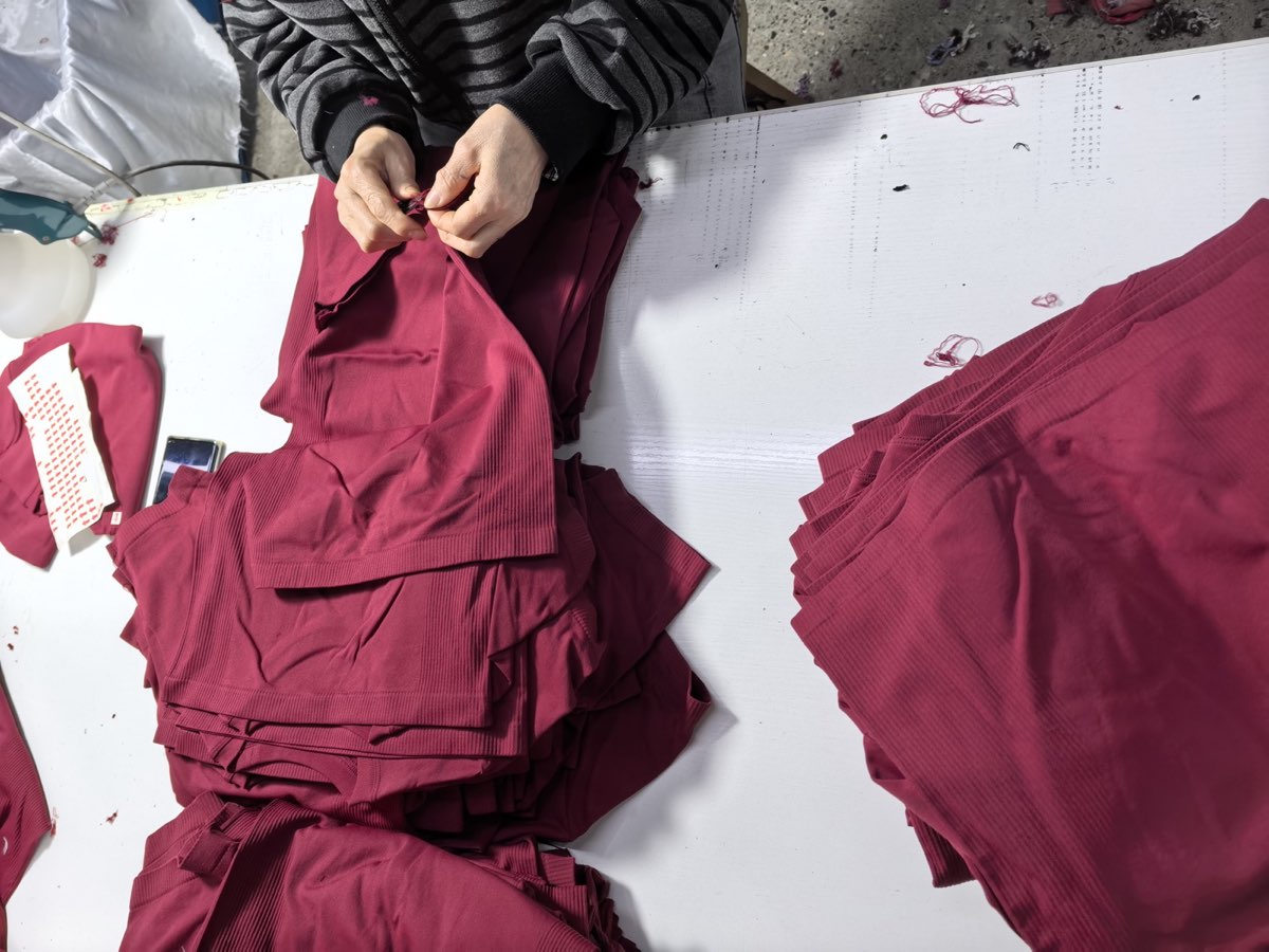 Operator trimming loose threads from finished garments